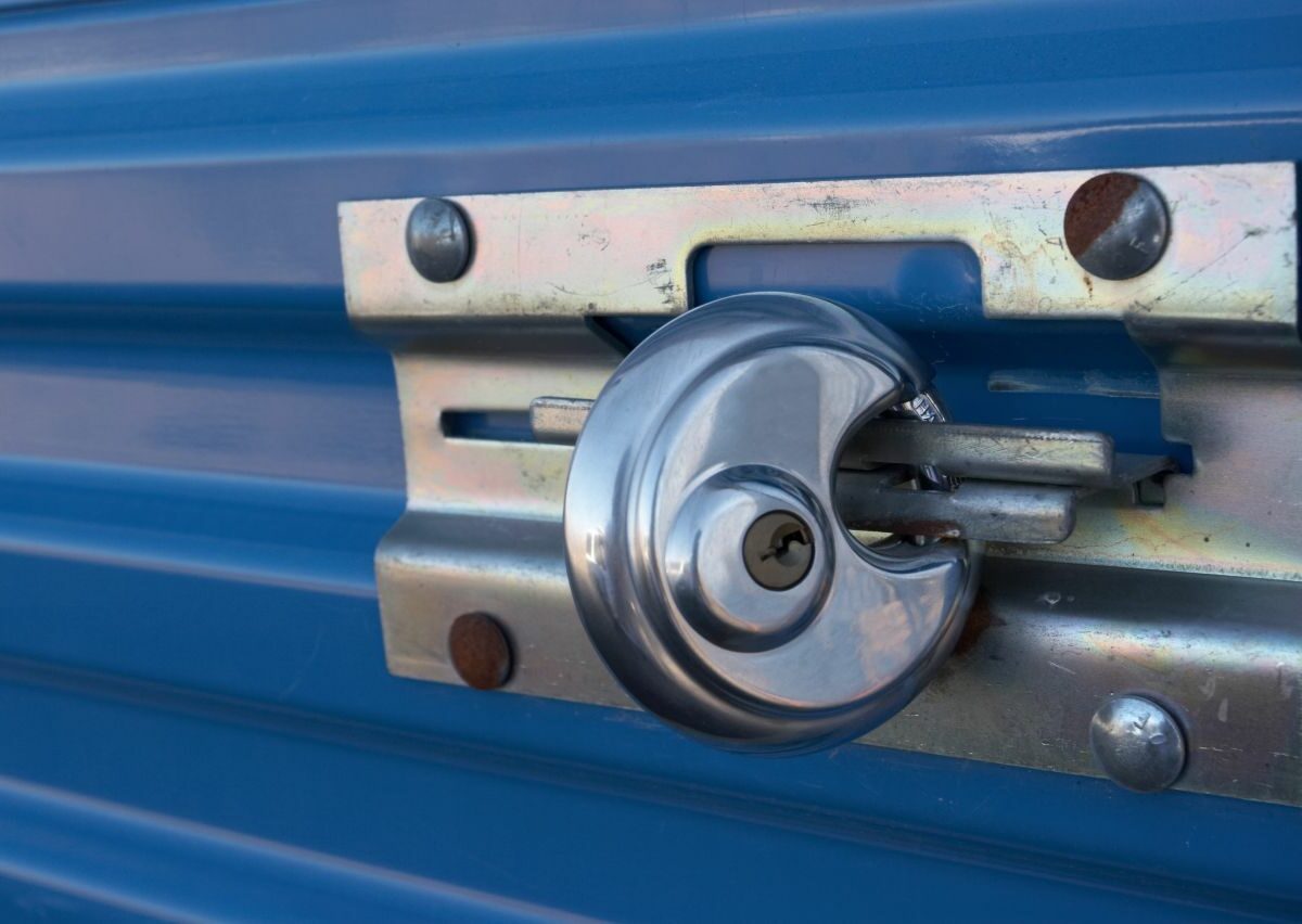A circular padlock is closed around the latch of a storage unit doo