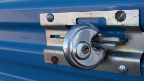 A circular padlock is closed around the latch of a storage unit doo