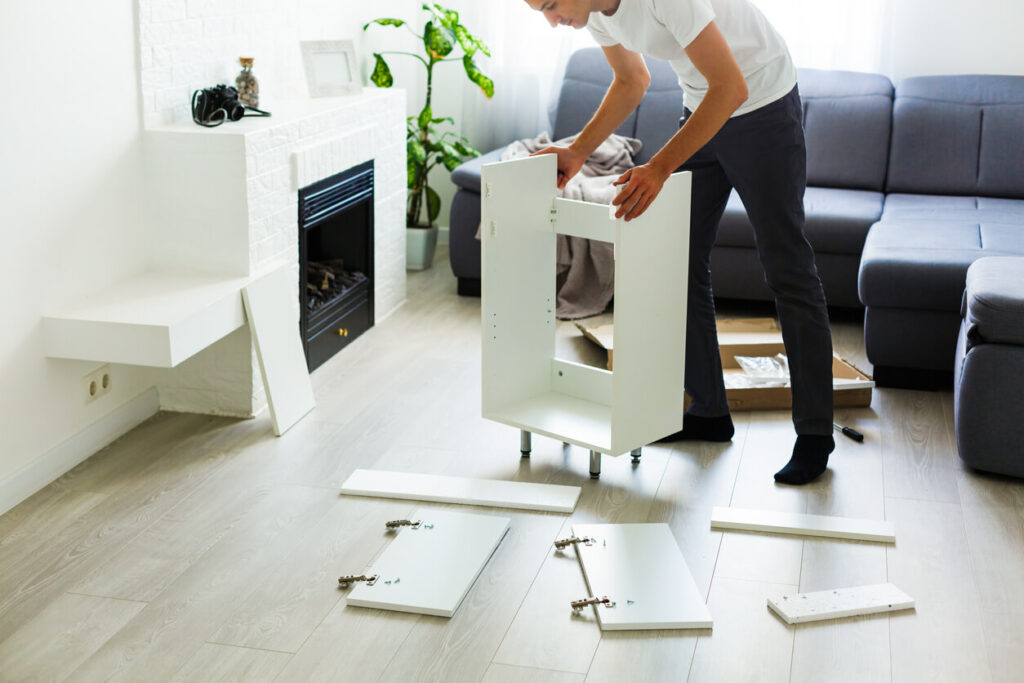 Man taking apart a cabinet with cabinet doors laying on the floor