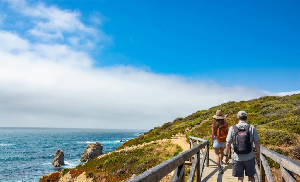 Couple walking down a wooden bridge along the beach