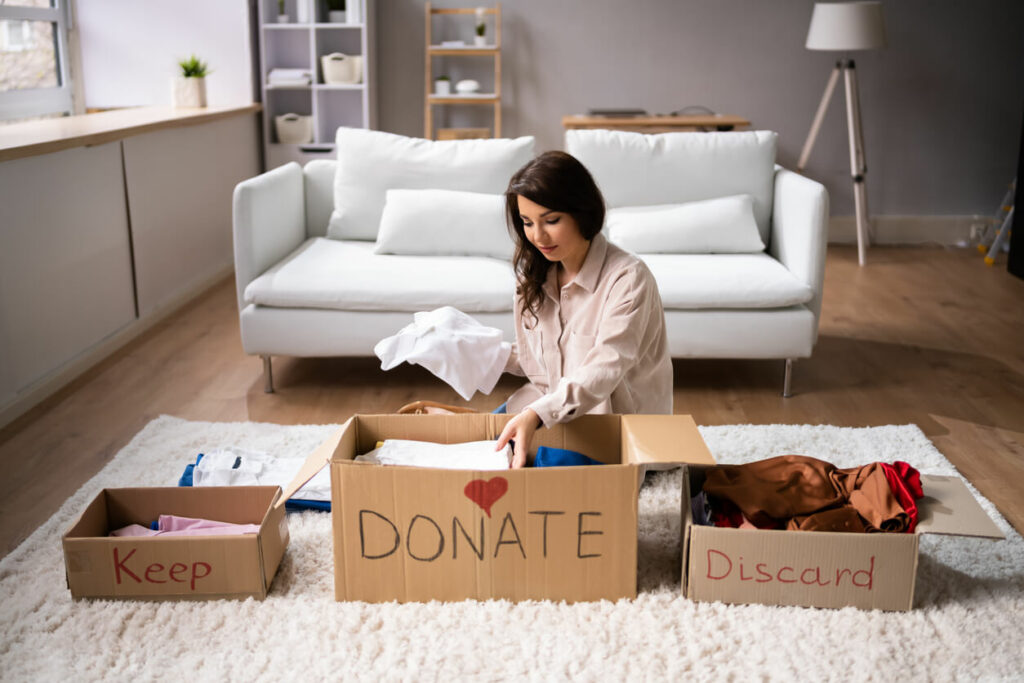 A woman sorting clothes into boxes and deciding what to keep.