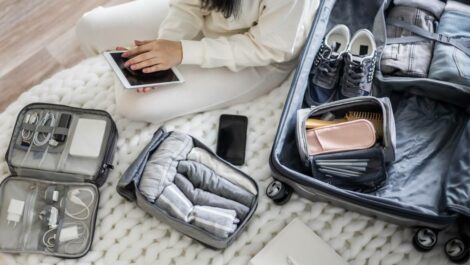 Young woman packing items in luggage for vacation.