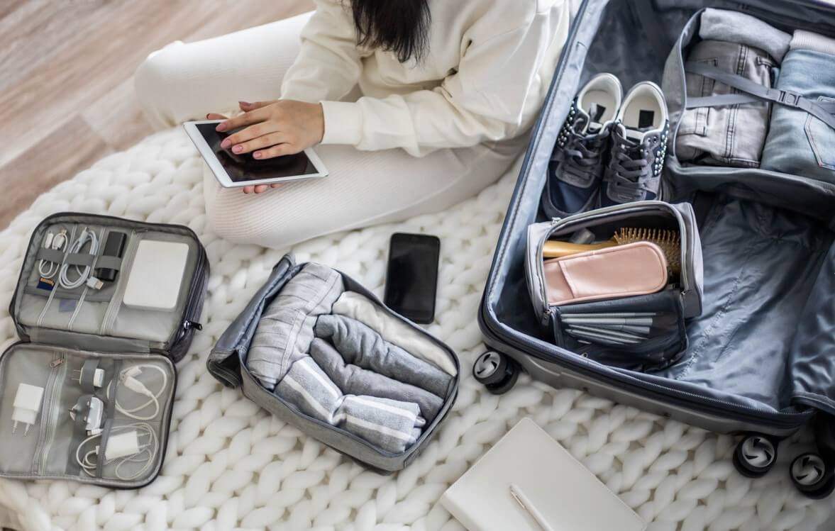 Young woman packing items in luggage for vacation.