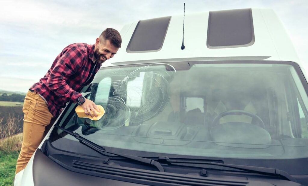 Man cleaning the windshield of an RV.