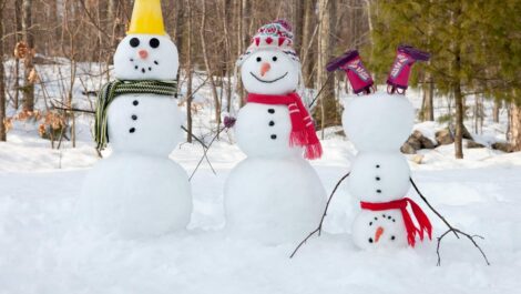 A family of snowmen, with the smallest one doing a headstand.