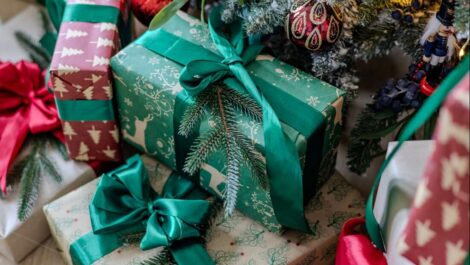 Wrapped gifts on the floor under a tree.