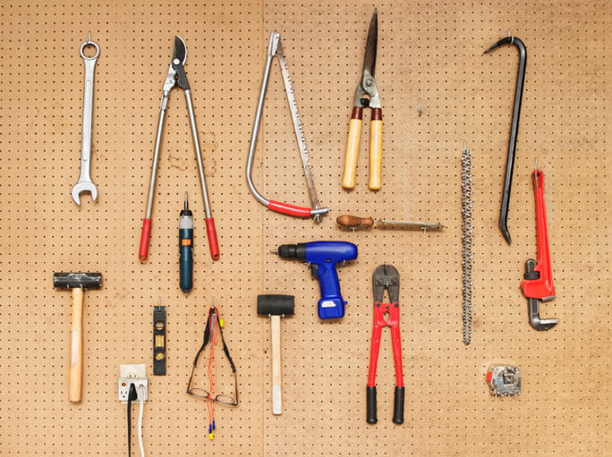 Assorted tools hanging on hooks on a basement wall