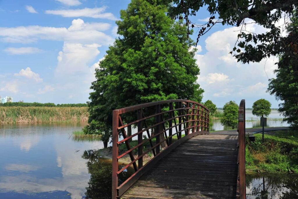 A wooden bridge across a grassy Florida lake on a sunny day.